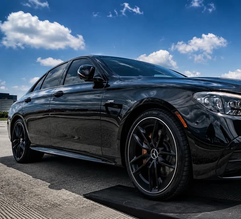 A black Mercedes-AMG sedan off the trailer and back on the ground under an open sky.